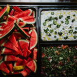 Fresh salads on display, watermelon slices, yoghurt dip